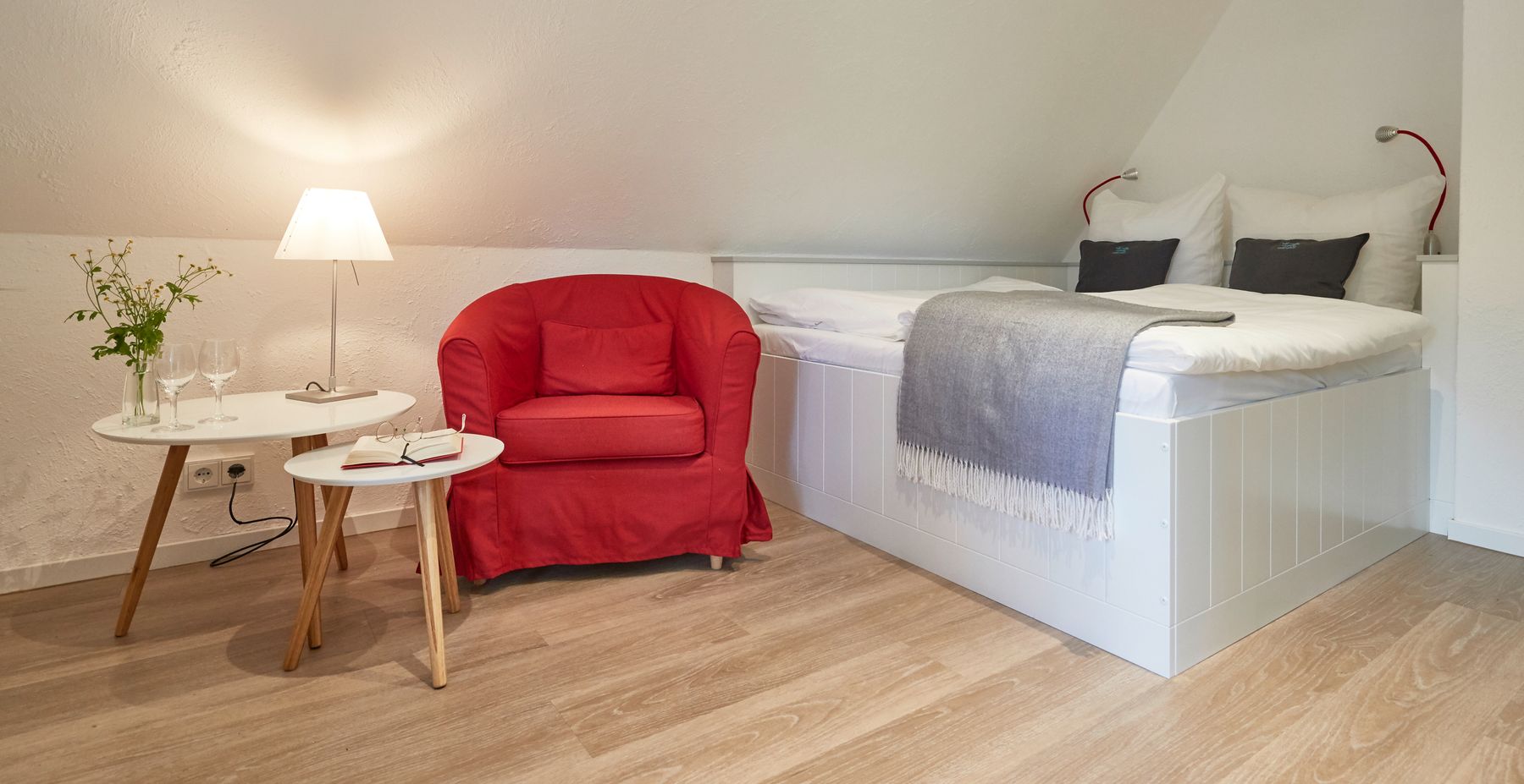 Gästezimmer mit Betten und rotem Sessel